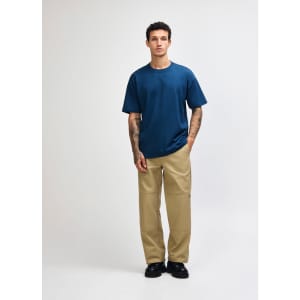 A model wearing a navy blue American Apparel Super Heavyweight T-Shirt paired with olive green cargo pants.