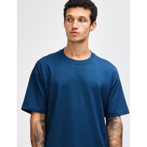 A model wearing a teal American Apparel Super Heavyweight T-Shirt, featuring a round neckline and short sleeves.