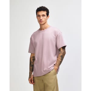 A model wearing a purple American Apparel Super Heavyweight T-Shirt, featuring short sleeves and a relaxed fit.