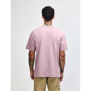 A person facing away wears a purple American Apparel Super Heavyweight T-Shirt, showing its back. The shirt has a subtle brand logo.