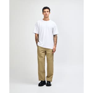 A man wearing a plain white American Apparel Super Heavyweight T-Shirt paired with light blue jeans and black shoes.
