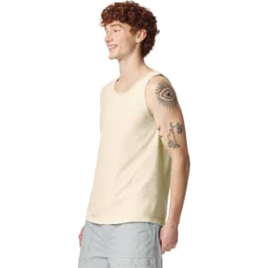 A light cream adult tank top displayed on a model with tattoos, featuring a logo on the side.