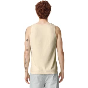 A light beige tank top on a model, featuring a plain back and a visible logo at the neckline.