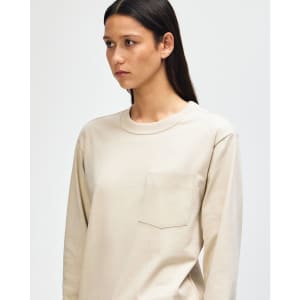 A model wearing a beige American Apparel Super Heavyweight T-Shirt with a pocket and a branded logo.