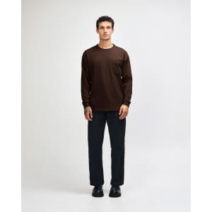 A model wearing a brown long-sleeve shirt with a pocket and green cargo pants, paired with sneakers.