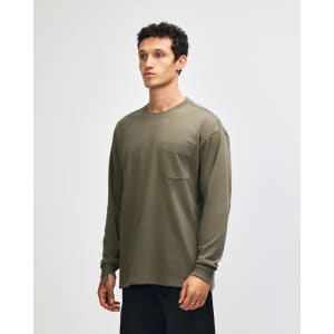 A long-sleeve, olive green t-shirt featuring a pocket and a logo, modelled by a young man.