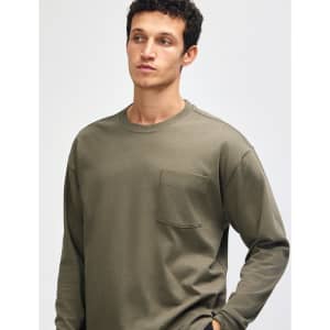 A model wearing an olive green American Apparel Super Heavyweight T-Shirt with a pocket. The shirt features long sleeves.