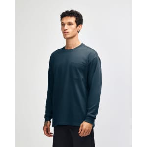 A long-sleeve navy T-shirt with a pocket and a logo. The model is wearing casual olive green pants.