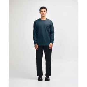 A model wears a navy long-sleeve T-shirt with a pocket, paired with olive green cargo pants and sneakers.