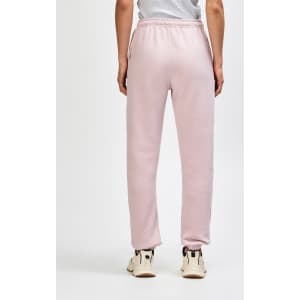 Unisex sweatpants in a soft pink hue, featuring elastic cuffs and a neat fit at the back. Brand logo present.