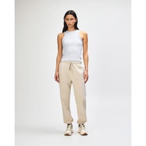 Unisex sweatpants in cream, paired with a pink sweatshirt, worn by a model standing in a neutral background.