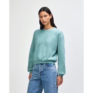 A teal women's crewneck sweatshirt with a relaxed fit and long sleeves, featuring a subtle logo.