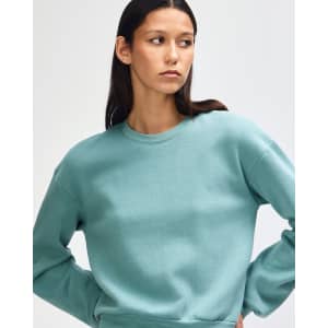 A teal women's crewneck sweatshirt made from fleece, featuring a simple design and a logo.