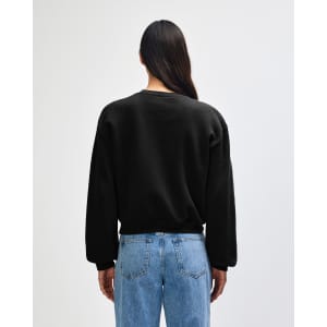 A black women's crewneck sweatshirt with a relaxed fit, viewed from the back. Features a logo on the garment.
