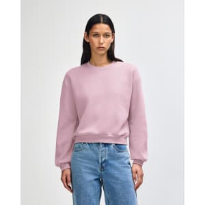 A women's crewneck sweatshirt in a soft pink colour, featuring a relaxed fit and long sleeves. It has a logo.
