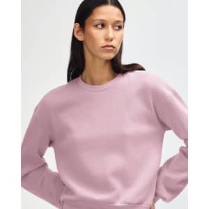 A women's crewneck sweatshirt in a soft pink hue. It features a relaxed fit and has a logo.