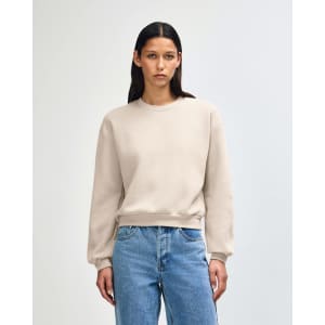 A women's crewneck sweatshirt in a beige colour, featuring a relaxed fit and long sleeves. It has a simple logo.