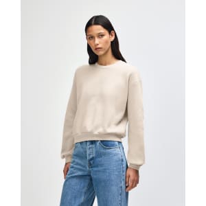 A cream women's crewneck sweatshirt with a relaxed fit, featuring long sleeves and a simple design.