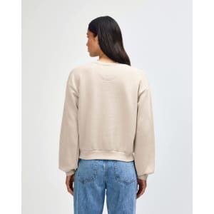 A women's crewneck sweatshirt in a light beige colour, featuring a relaxed fit and long sleeves. It has a logo.