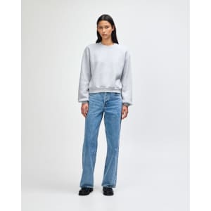 A grey women's crewneck sweatshirt with long sleeves, semi-fitted style, worn with light blue jeans.