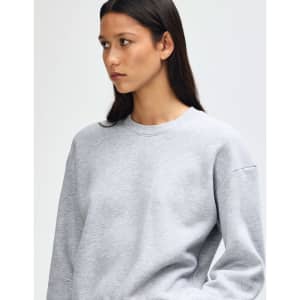 A grey women's crewneck sweatshirt with a relaxed fit and long sleeves. It features a logo on the front.