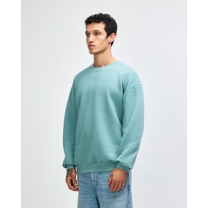 A unisex crewneck sweatshirt in a soft green colour, featuring a relaxed fit and ribbed cuffs. It has a logo.