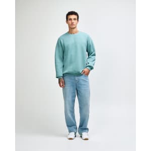 A unisex crewneck sweatshirt in green, paired with black cargo pants, featuring a logo on the front.