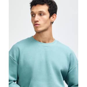 A unisex crewneck sweatshirt in green, featuring a relaxed fit and a simple design. It has a logo on it.