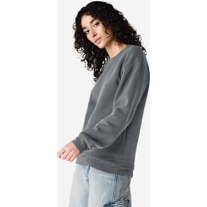 A unisex crewneck sweatshirt in grey, featuring long sleeves and a relaxed fit. It includes a logo.