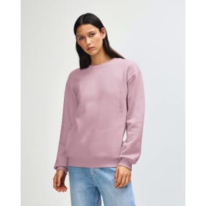 A unisex crewneck sweatshirt in light pink, featuring a relaxed fit and long sleeves. It has a logo on the front.