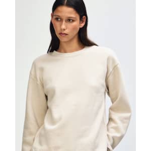 A unisex crewneck sweatshirt in cream with a relaxed fit. It features a subtle logo and soft fleece material.