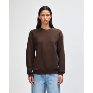 A unisex crewneck sweatshirt in dark brown, featuring long sleeves and a casual fit. The garment has a logo.