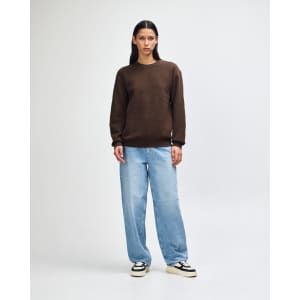 A unisex crewneck sweatshirt in brown worn with light blue cargo pants, featuring a simple design and a logo.