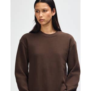 A unisex crewneck sweatshirt in a rich brown colour, featuring long sleeves and a standard fit. It has a logo.