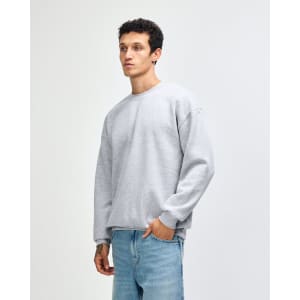 A unisex crewneck sweatshirt in light grey, featuring a relaxed fit and ribbed cuffs. It has a logo on it.