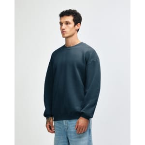 A unisex crewneck sweatshirt in teal, featuring a relaxed fit and a logo on the sleeve.