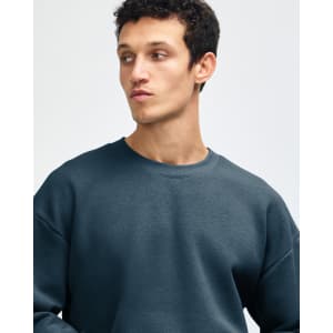A unisex crewneck sweatshirt in deep teal, featuring long sleeves and a relaxed fit, with a logo present.