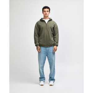 A model wearing an olive green unisex full zip hooded sweatshirt paired with light blue oversized jeans.