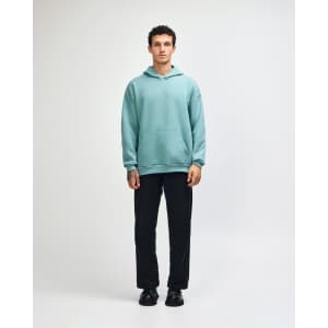 A unisex hooded sweatshirt in mint green, paired with black cargo pants and sneakers, featuring a logo.