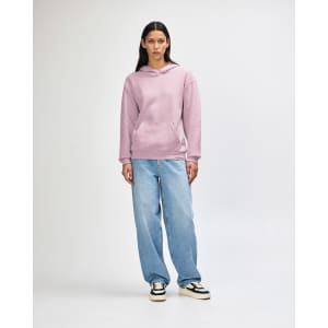 A unisex hooded sweatshirt in pink, featuring a front pocket and a logo, worn with light blue jeans.