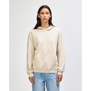 A unisex hooded sweatshirt in a light beige colour, featuring a front pocket and a hood. It has a branding logo.