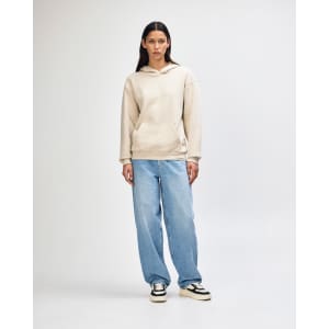 A unisex hooded sweatshirt in beige featuring a front pocket and a soft fleece material, worn with light blue jeans.