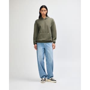 A model wearing an olive green unisex hooded sweatshirt, paired with black cargo pants and sneakers.