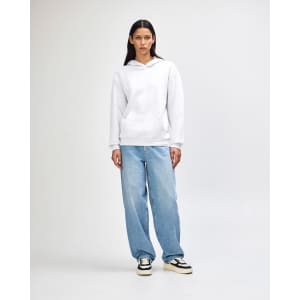 A unisex hooded sweatshirt in white, featuring a front pocket and a plain design. The model wears casual light blue jeans.