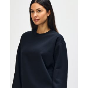 A black Gildan Softstyle adult sweatshirt displayed on a model, featuring a simple design and round neckline.