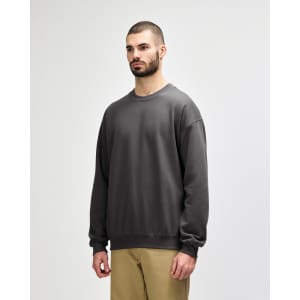 A green Gildan Softstyle adult sweatshirt displayed on a model, featuring long sleeves and a classic fit.