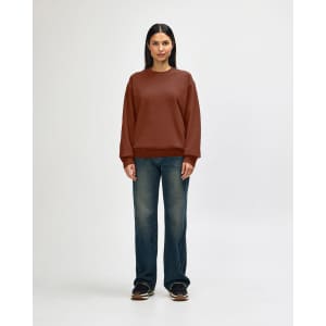 A brown Gildan Softstyle adult sweatshirt is worn by a model, paired with black pants and sneakers.