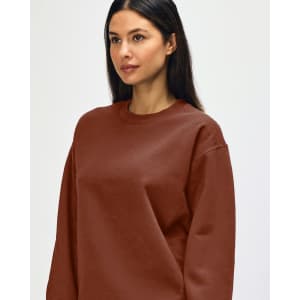 A brown Gildan Softstyle adult sweatshirt worn by a model, featuring a simple design and a logo.