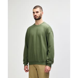 A green Gildan Softstyle adult sweatshirt is displayed on a model, featuring a simple design and a logo.