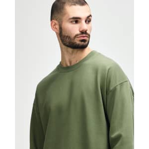 A model wearing an olive green Gildan Softstyle adult sweatshirt. The sweatshirt has a round neckline and long sleeves.